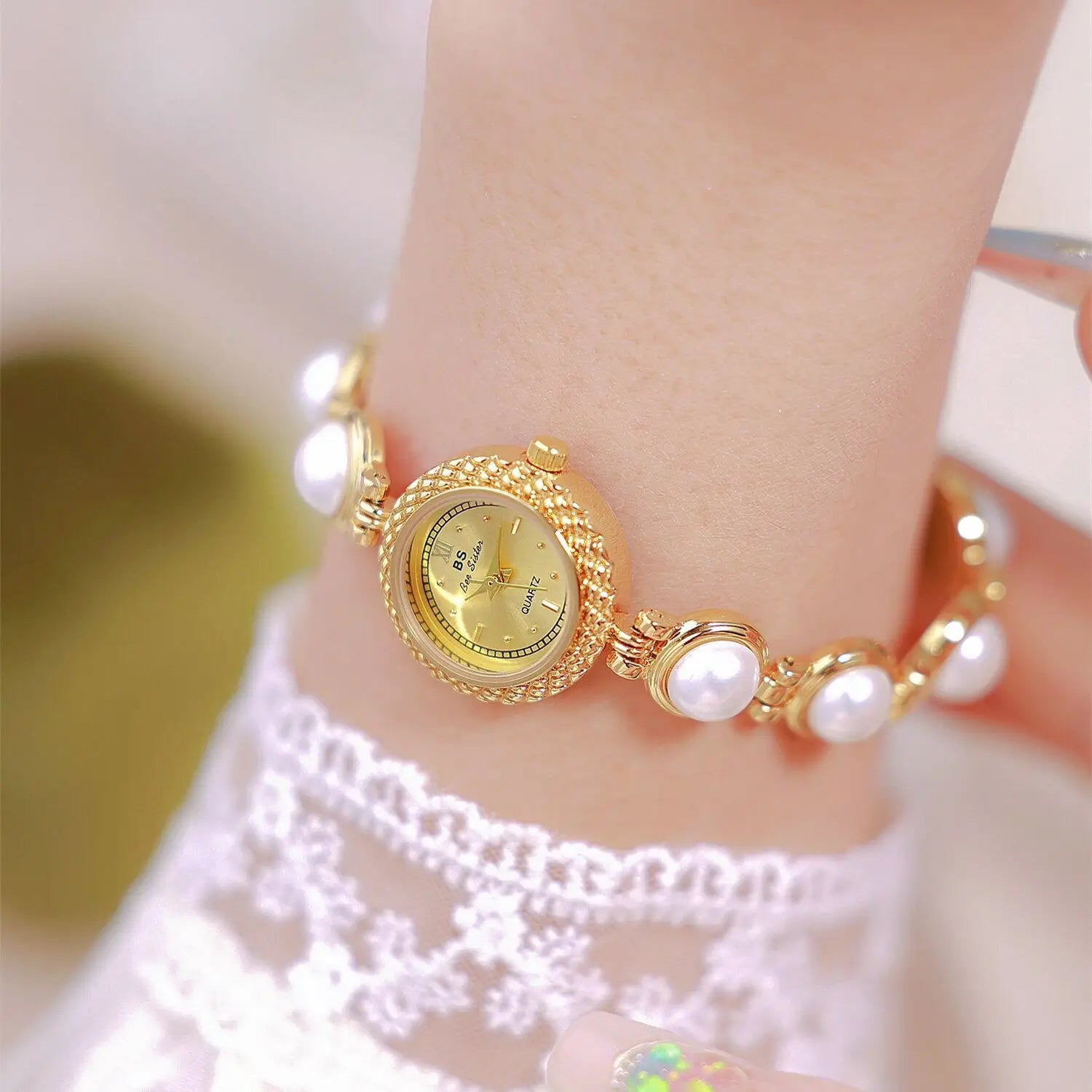 Elegant pearl bracelet quartz watch for women featuring a gold-toned design with pearl adornments, a delicate textured bezel, and matching bracelet links.