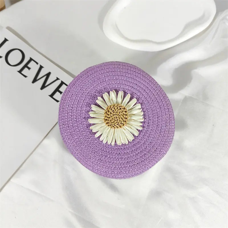purple woven straw crossbody bag adorned with a white daisy embellishment designed as a round shoulder purse