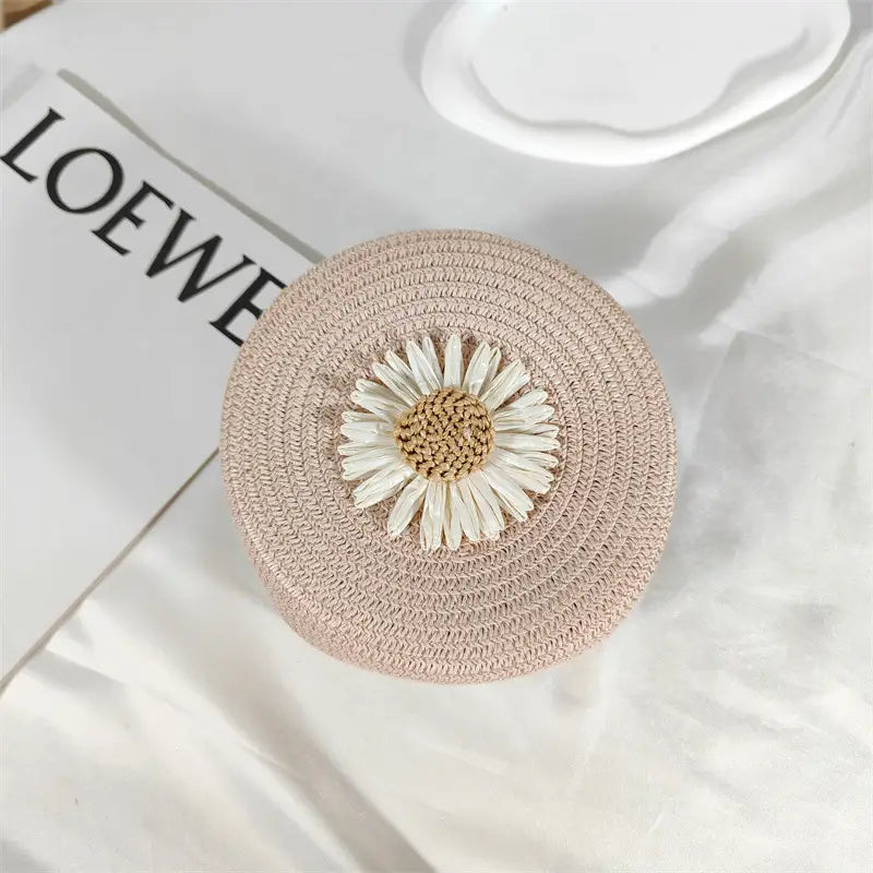 a delicate beige woven straw daisy straw crossbody bag round woven shoulder purse adorned with a white daisy embellishment featuring a textured brown center