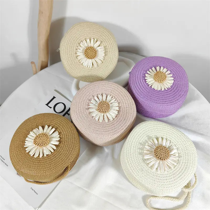 Daisy straw crossbody bags round woven shoulder purses in beige lavender taupe and cream with a white daisy appliqué featuring a tan center.