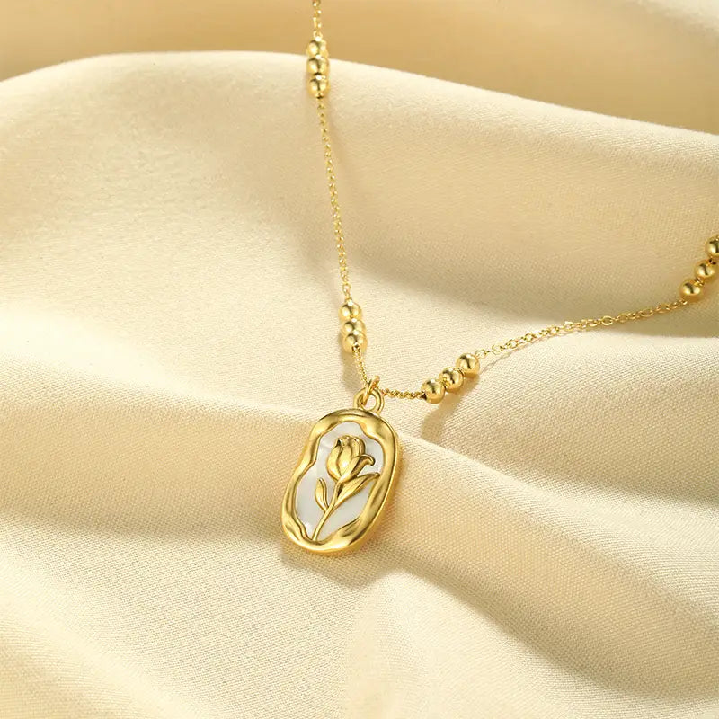 18k gold plated stainless steel necklace featuring a gold-toned oval pendant with a delicate tulip design on a white mother-of-pearl-like background.
