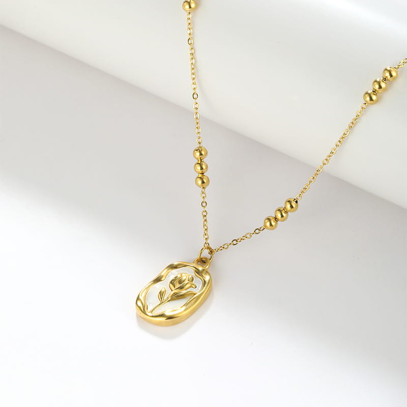 18k gold plated stainless steel necklace featuring a gold-toned delicate chain with spherical beads and an oval pendant engraved with a rose design.