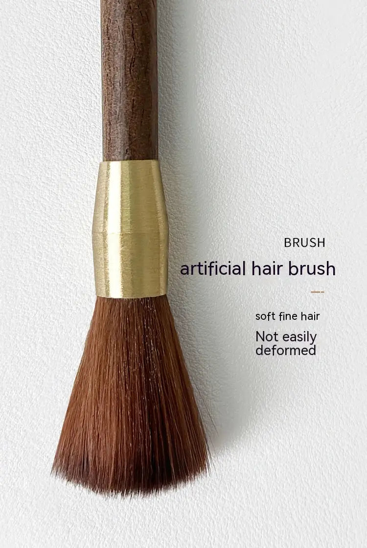 A sleek coffee grinder cleaning brush with a dark wood handle, polished gold brass band, and dense brown synthetic bristles.