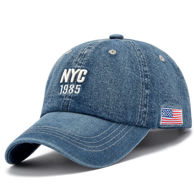 Men denim NYC baseball cap made of faded blue denim featuring white NYC 1985 embroidery on the front and a small American flag patch on the side.