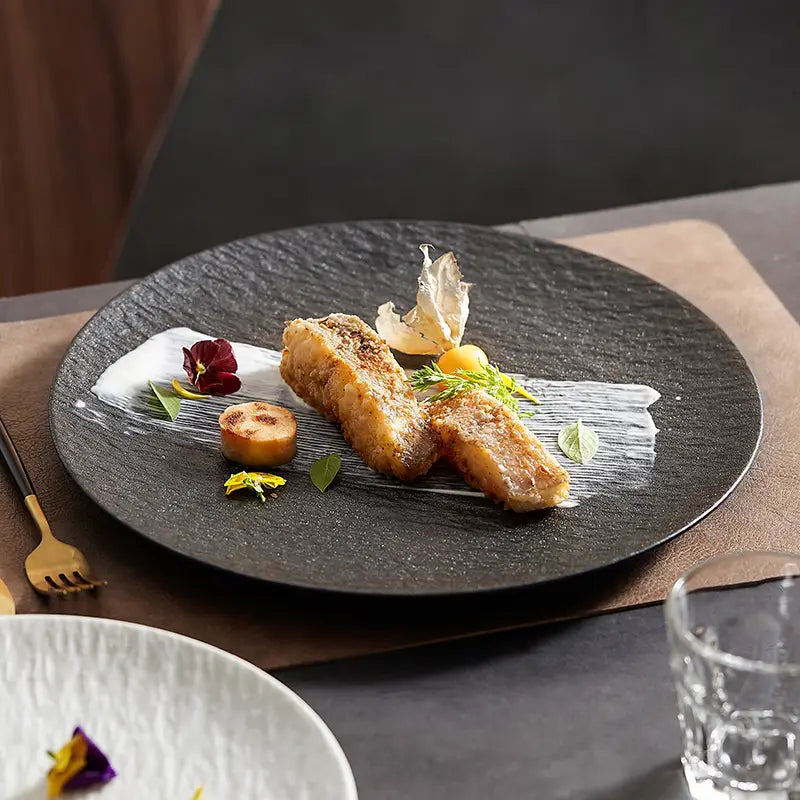 Black textured ceramic round plate featuring a nordic rock pattern suitable for serving.