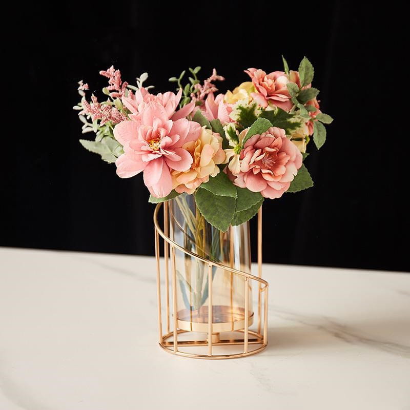gold metal spiral candle holder with glass cylinder featuring a delicate rose bouquet in a modern gold-toned metal cage vase with a clear glass center