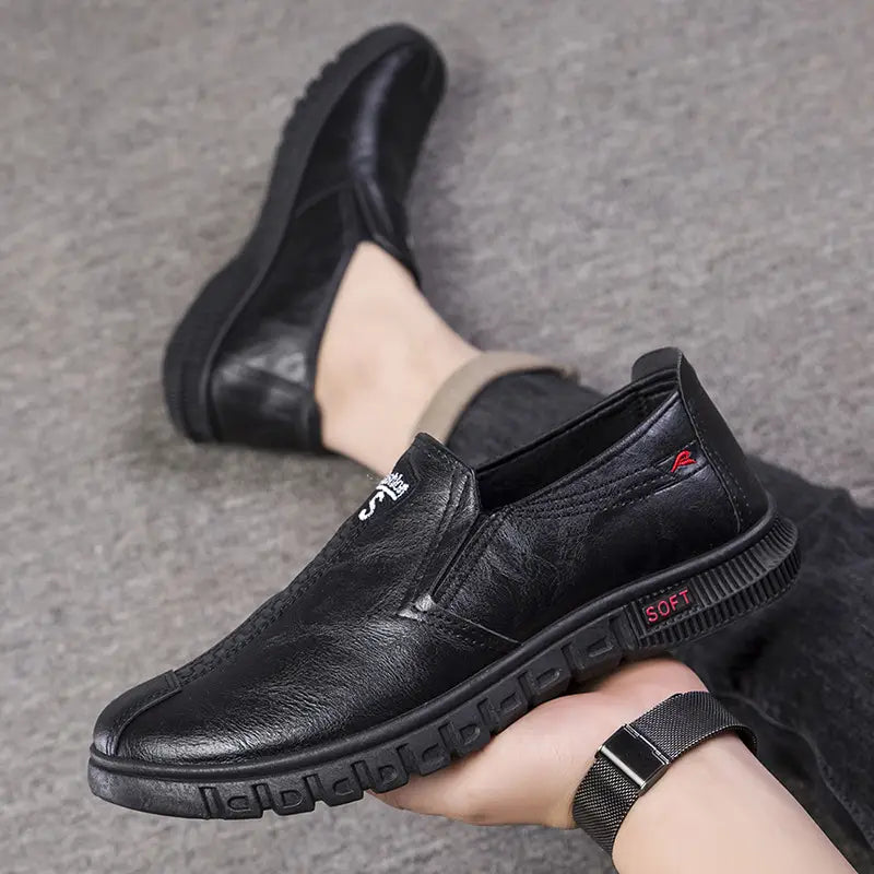 Mocassin de chef noir en cuir, enfiler, avec une semelle texturée antidérapante et un marquage rouge souple sur le talon, présenté depuis l’arrière.