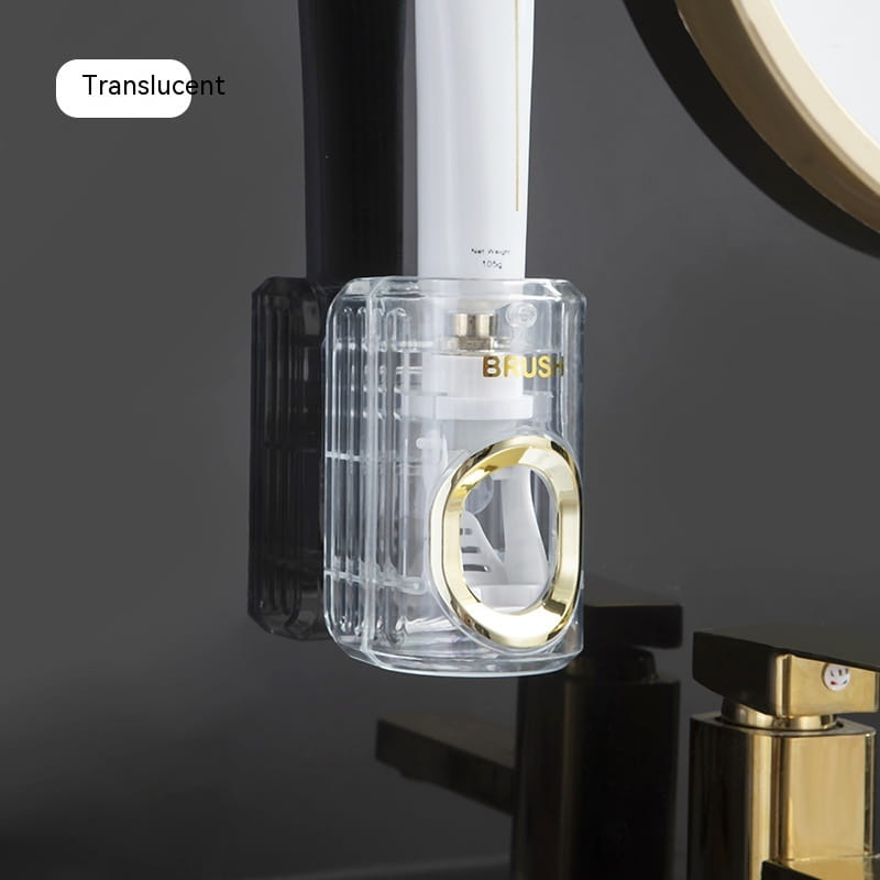 Translucent acrylic automatic toothpaste dispenser and toothbrush holder with gold-accented circular opening and vertical ridged design.