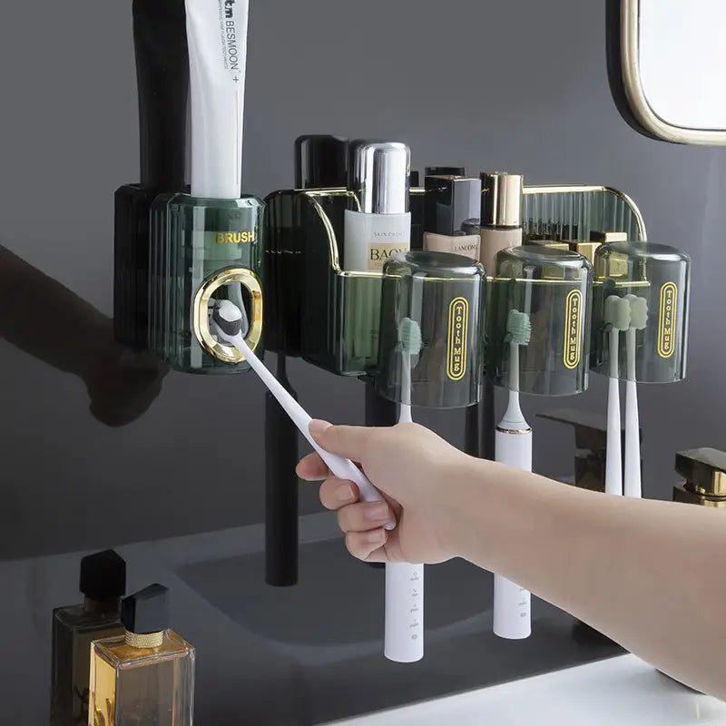 Emerald green automatic toothpaste dispenser and toothbrush holder with gold accents and labeled compartments for brush, toothpaste, and electric toothbrushes.