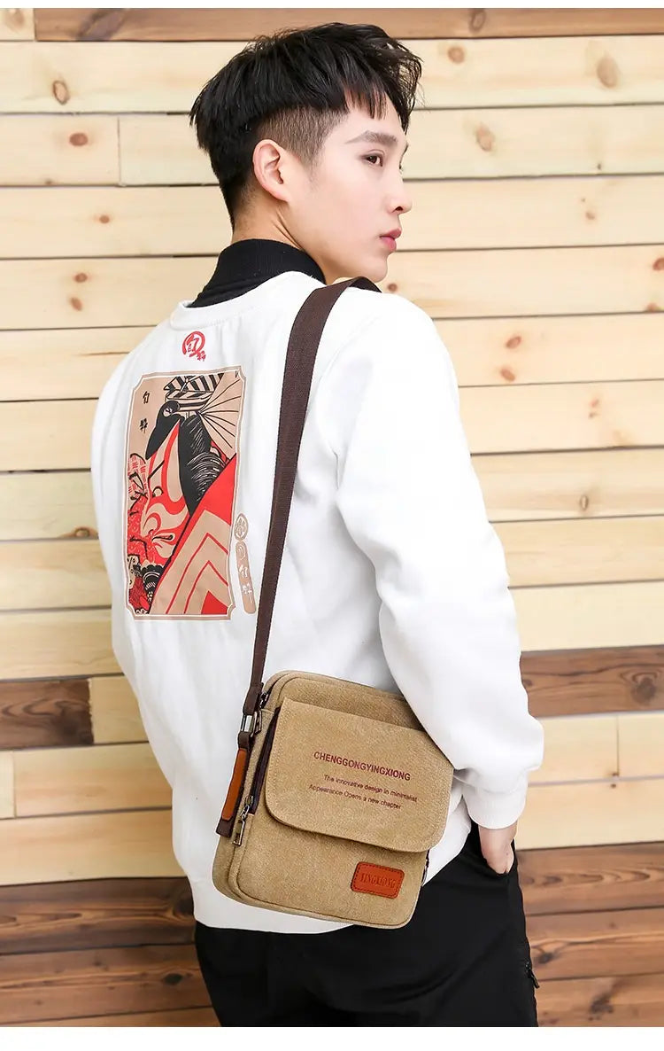 Men’s canvas crossbody business shoulder bag in tan with a brown leather strap and a small rectangular patch on the front.