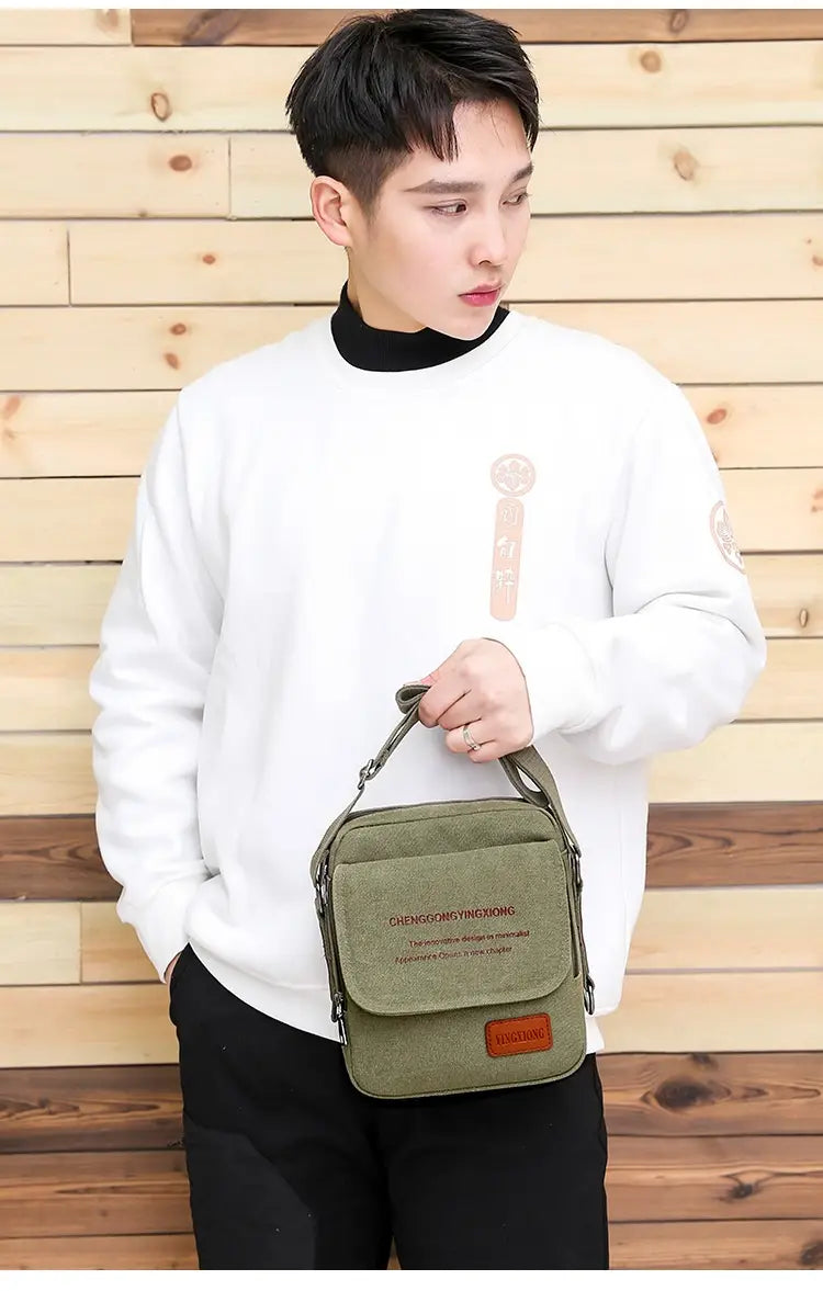 Men’s canvas crossbody business shoulder bag in olive green with a brown leather patch and black stitching made of durable canvas material.