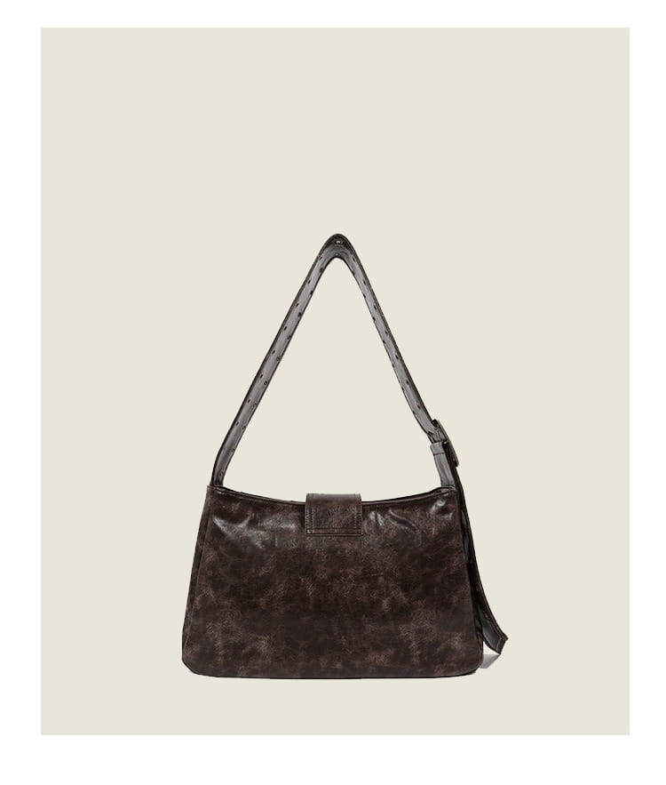 Brown leather punk crossbody bag with rivets made of dark brown distressed leather featuring a subtle marbled texture and a matching adjustable shoulder strap.