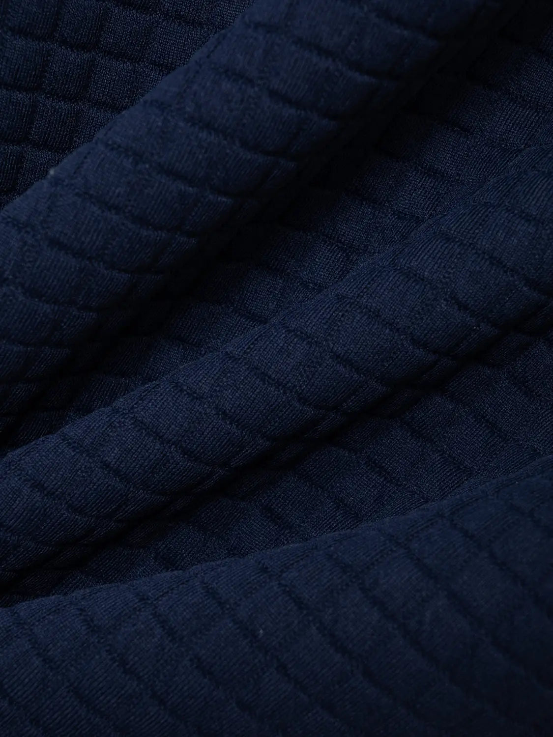 Dunkelblauer, wattierter Stoff mit einem strukturierten, gerippten Muster, präsentiert am Herren-Jacquard-Karree-Sportpolohemd mit Kontrastbesatz.