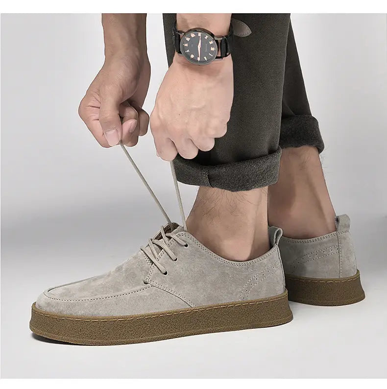 Chaussures plates décontractées à lacets en daim gris pour hommes, avec une semelle en caoutchouc marron.