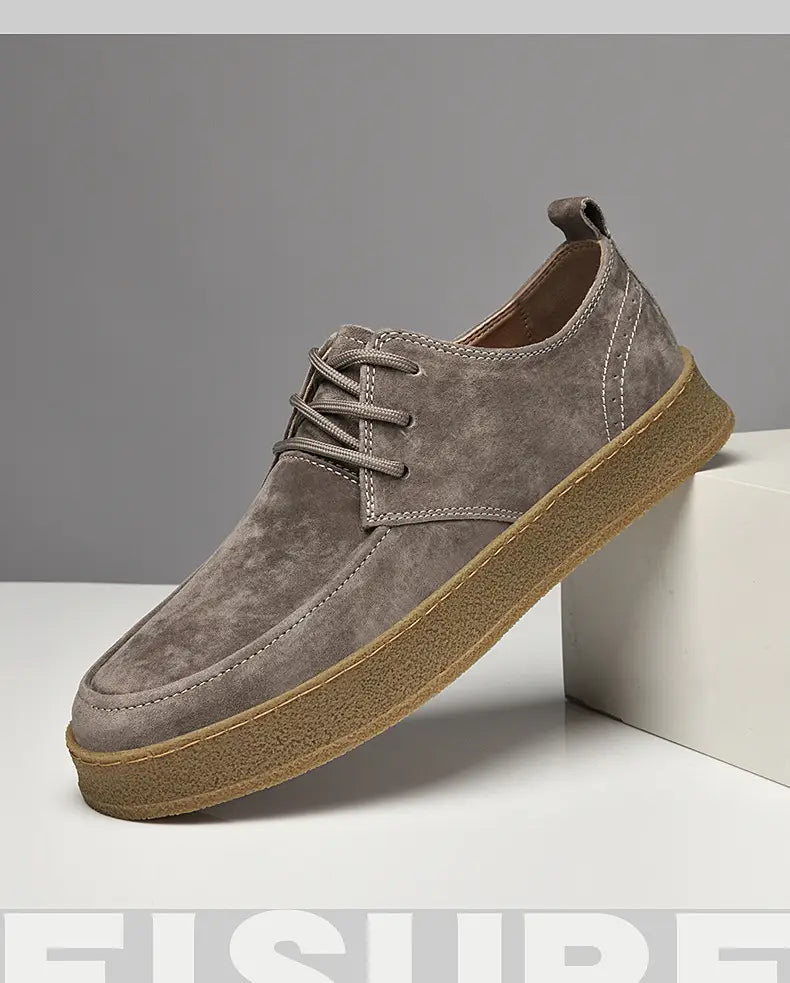 Chaussures plates décontractées à lacets en daim gris pour hommes, dotées d’une semelle en caoutchouc couleur tan.