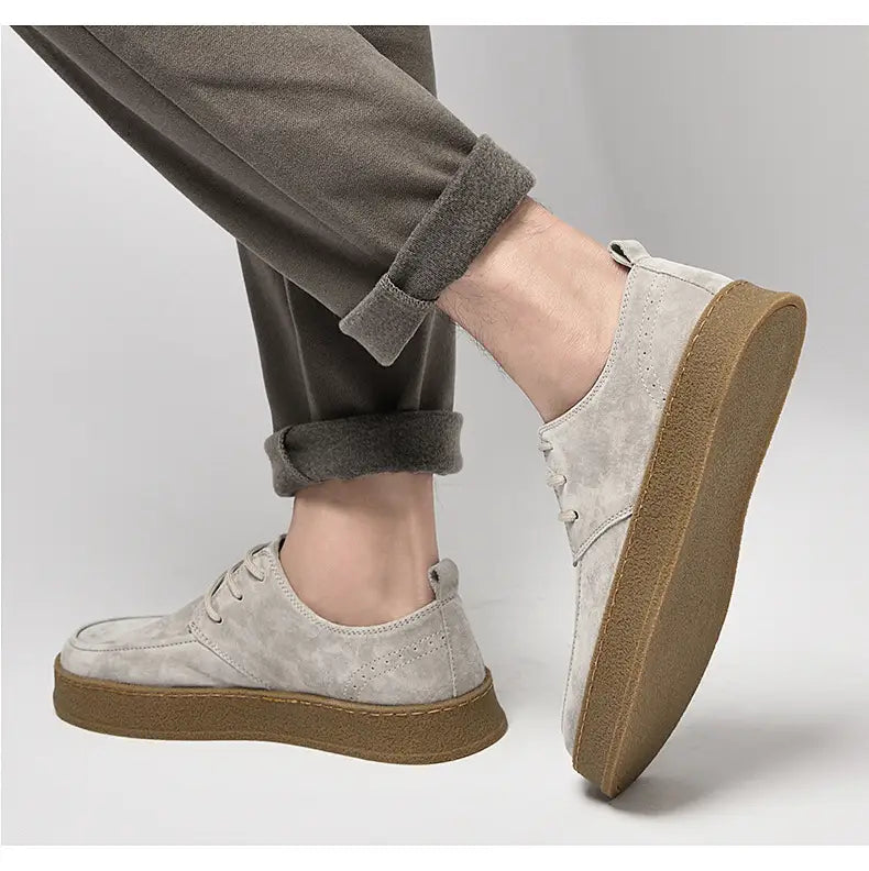 Chaussures plates décontractées à lacets en daim gris pour hommes, avec dessus en daim gris clair et semelle en caoutchouc marron épaisse.