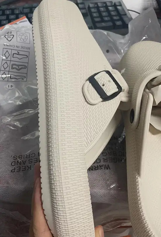 Men lightweight mesh clog slippers in cream color with a textured rubber sole and an adjustable black buckle strap.