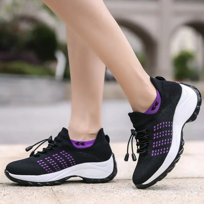 Women’s lightweight fly knit casual sneakers in black and purple with a mesh upper, white rubber sole, and adjustable laces.