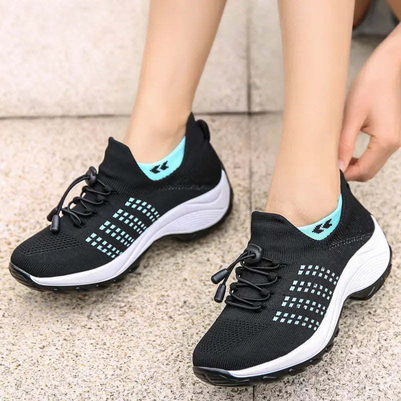 women’s lightweight fly knit casual sneakers in black with light blue accents and a white midsole made from breathable knit material.