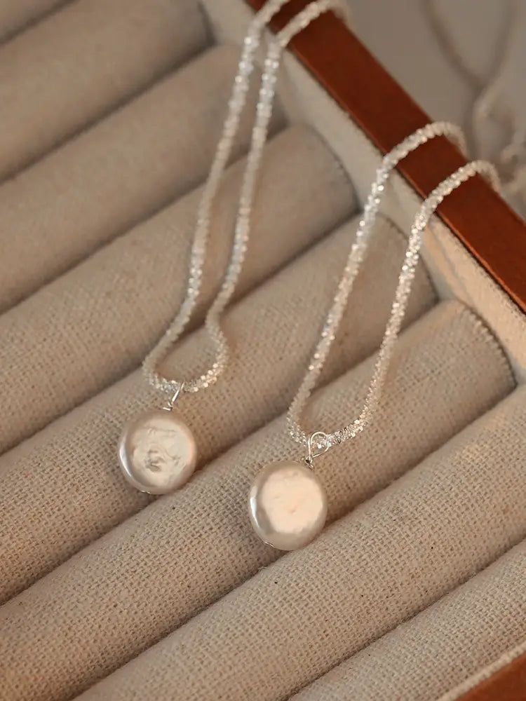 Sterling silver baroque pearl starry sky necklace with a silver-toned delicate textured chain and two round pearl-like pendants.
