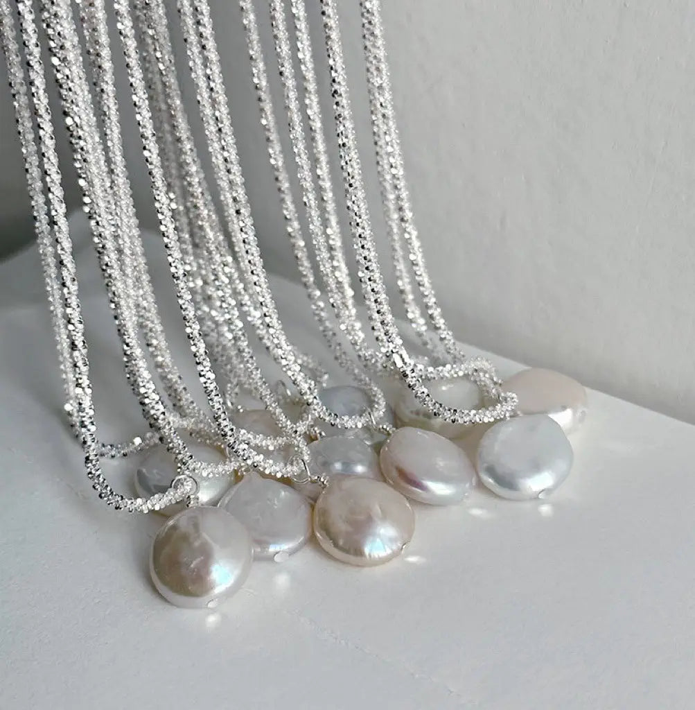 Sterling silver chain necklaces featuring dangling iridescent freshwater baroque pearl pendants designed as starry sky jewelry.
