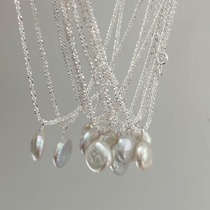 Sterling silver baroque pearl starry sky necklace featuring silver chain with dangling irregularly shaped freshwater pearls with a lustrous iridescent sheen.
