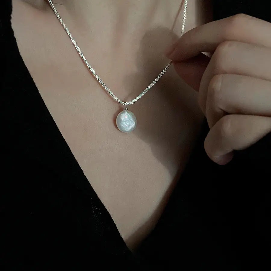 Sterling silver baroque pearl starry sky necklace featuring a delicate silver chain and a single oval-shaped white pearl pendant with subtle rose engraving.