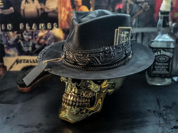 black leather Plush Skull cowboy hat featuring an intricate silver tooled band and a playing card tucked into its side