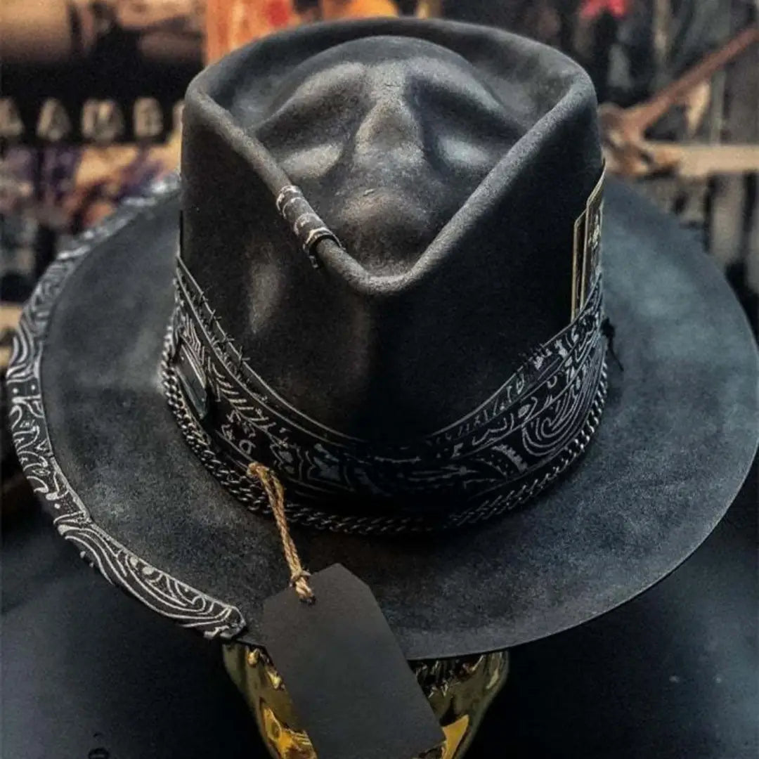 Plush skull cowboy hat in black featuring a wide brim fedora style with intricate white bandana-patterned trim and decorative stitching along the crown.