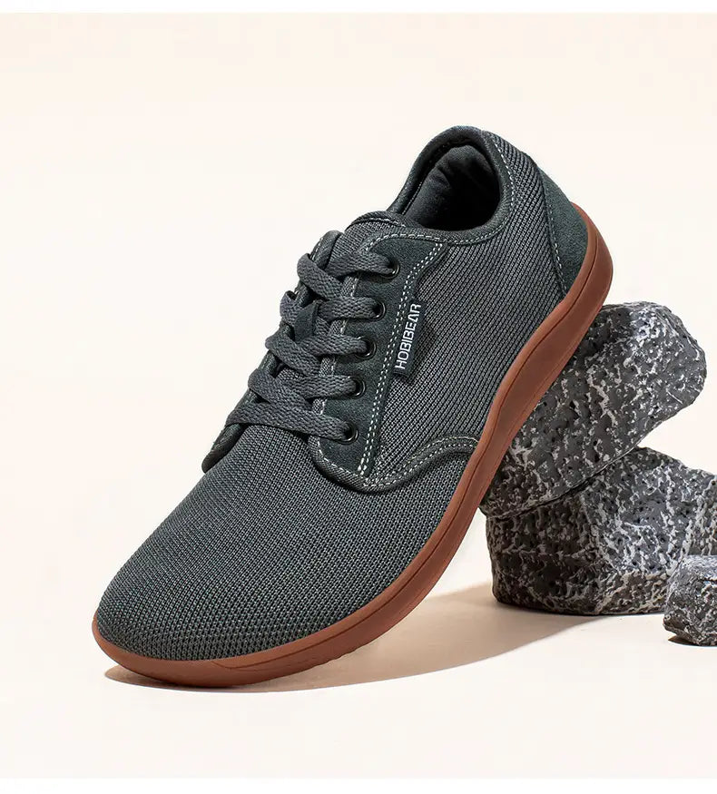 Chaussure de sport décontractée en daim unisexe gs6968 en maille gris foncé, semelle en caoutchouc marron, lacets noirs et étiquette de marque hobiegear sur le côté.