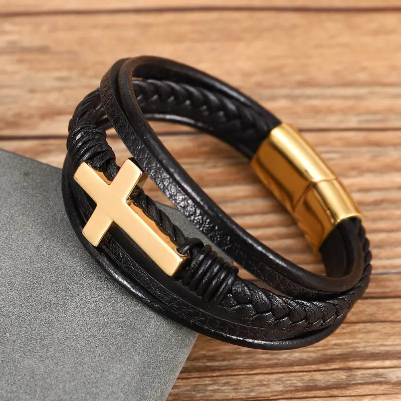 Black braided leather multi-strand bracelet with a gold-tone cross pendant and magnetic clasp.