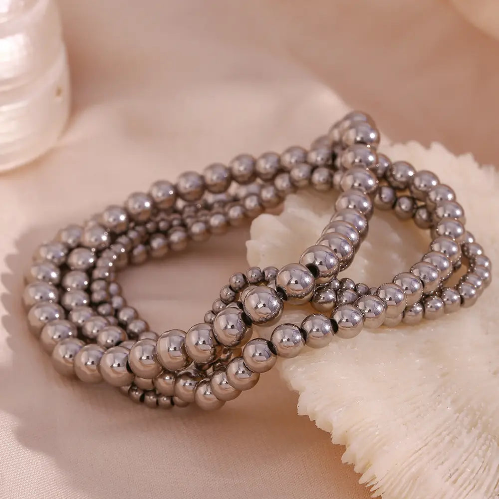 A multi-strand 18k gold plated stainless steel elastic bead bracelet with uniformly sized polished metallic beads in a reflective silver finish.
