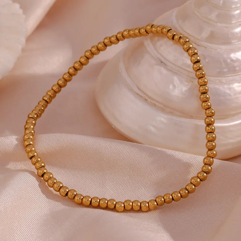 18k gold plated stainless steel elastic bead bracelet featuring gold-toned uniformly sized round beads.