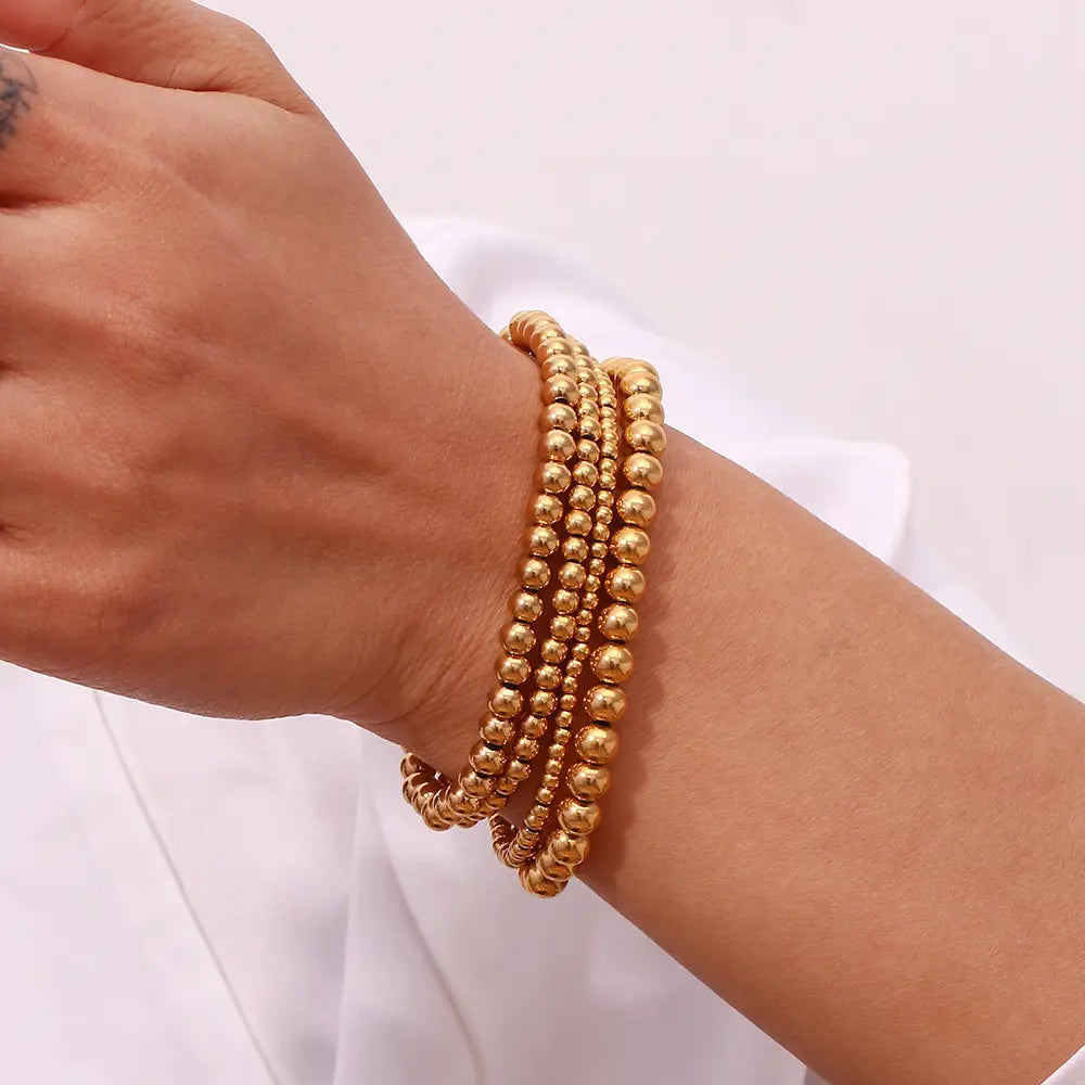 18k gold plated stainless steel elastic bead bracelet featuring a layered design with uniformly sized gold-toned spherical beads.