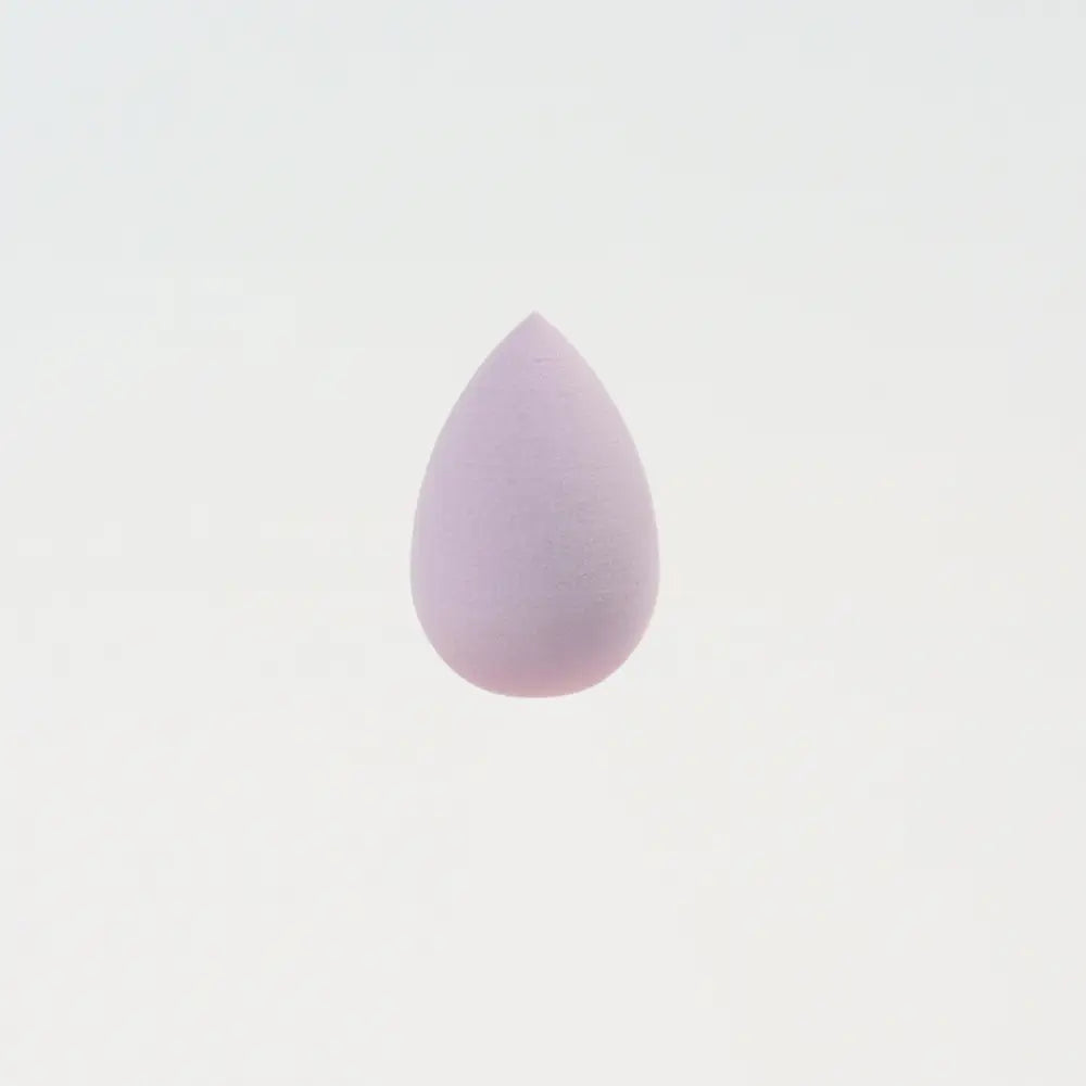 Une mini éponge de maquillage en silicone lilas doux, de forme goutte, conçue pour estomper harmonieusement le maquillage.