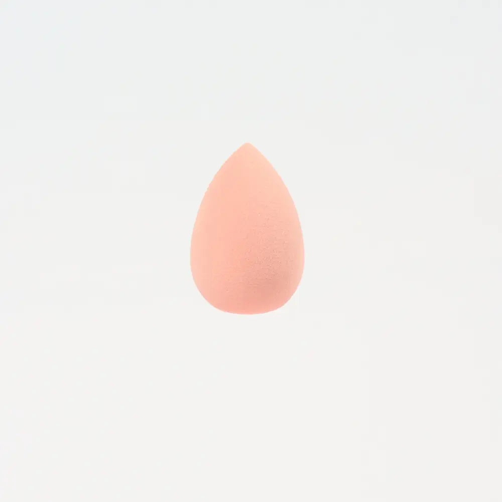 Une mini éponge de maquillage lilas pêche doux, de forme goutte et à surface poreuse lisse, conçue pour estomper harmonieusement le maquillage.