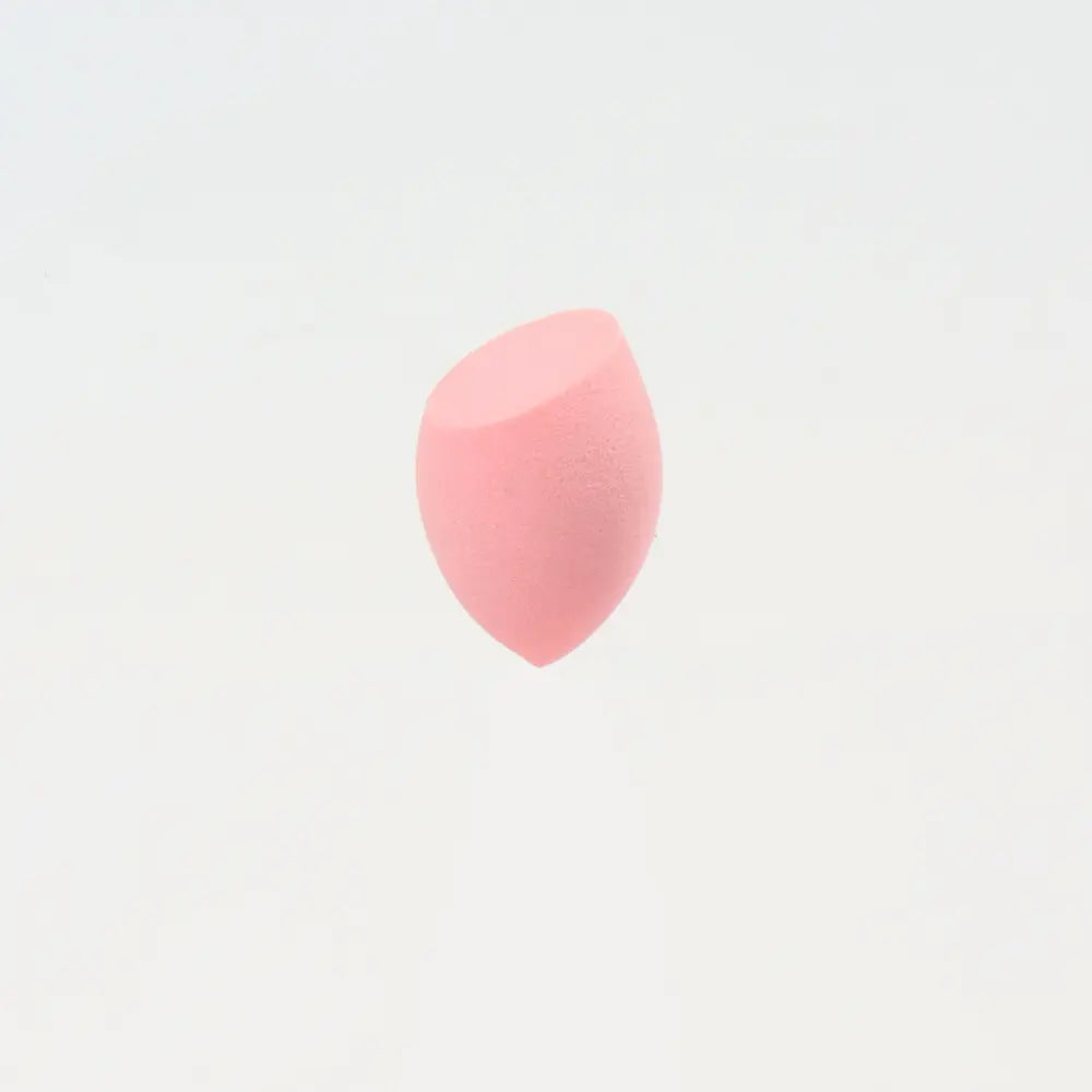 Une mini éponge de maquillage rose pâle, en forme de goutte, à surface lisse légèrement texturée, conçue pour une application avec beauty blender.