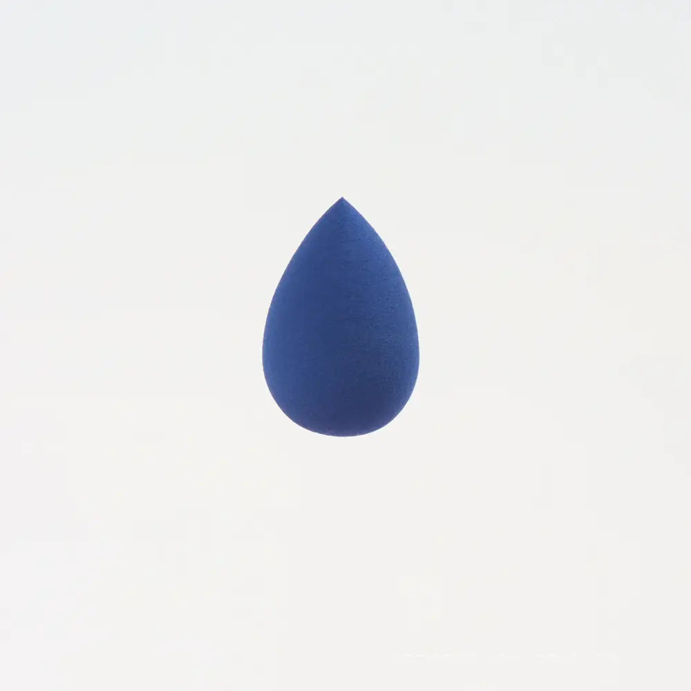 Une mini éponge de maquillage en forme de goutte bleu marine, fabriquée dans une matière douce, conçue pour estomper et appliquer des produits de beauté.