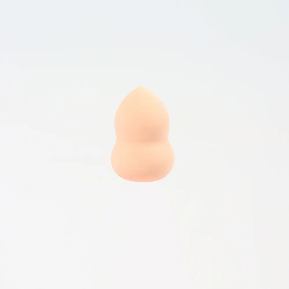 Une mini éponge de maquillage lilas pêche doux en forme de goutte, à surface lisse légèrement texturée, conçue pour un estompage précis du maquillage.