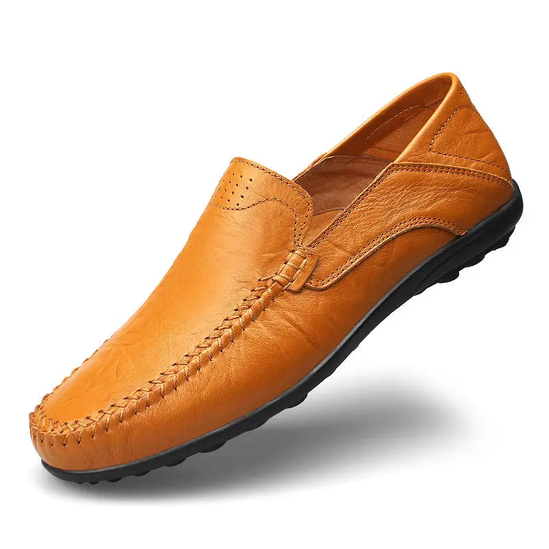 Mocasines sin cordones tipo loafer de cuero de badana color camel, transpirables, con perforaciones tipo gommino, con suela de goma negra y costuras decorativas.