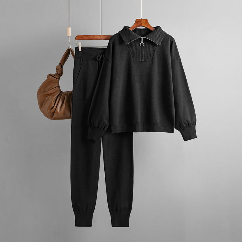 Conjunto de chándal de punto negro con un jersey de punto de cuello acanalado y detalle de cremallera frontal, combinado con joggers negros a juego.
