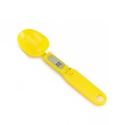 Yellow digital spoon scale made of plastic with a small lcd screen displaying 0.0 and buttons for measurement settings featuring an integrated handle with a hole at the end.
