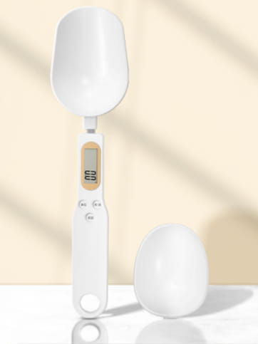 White digital spoon scale with a sleek minimalist design and an oval-shaped measuring spoon attached on top for precise 500g LCD measurement tool set.