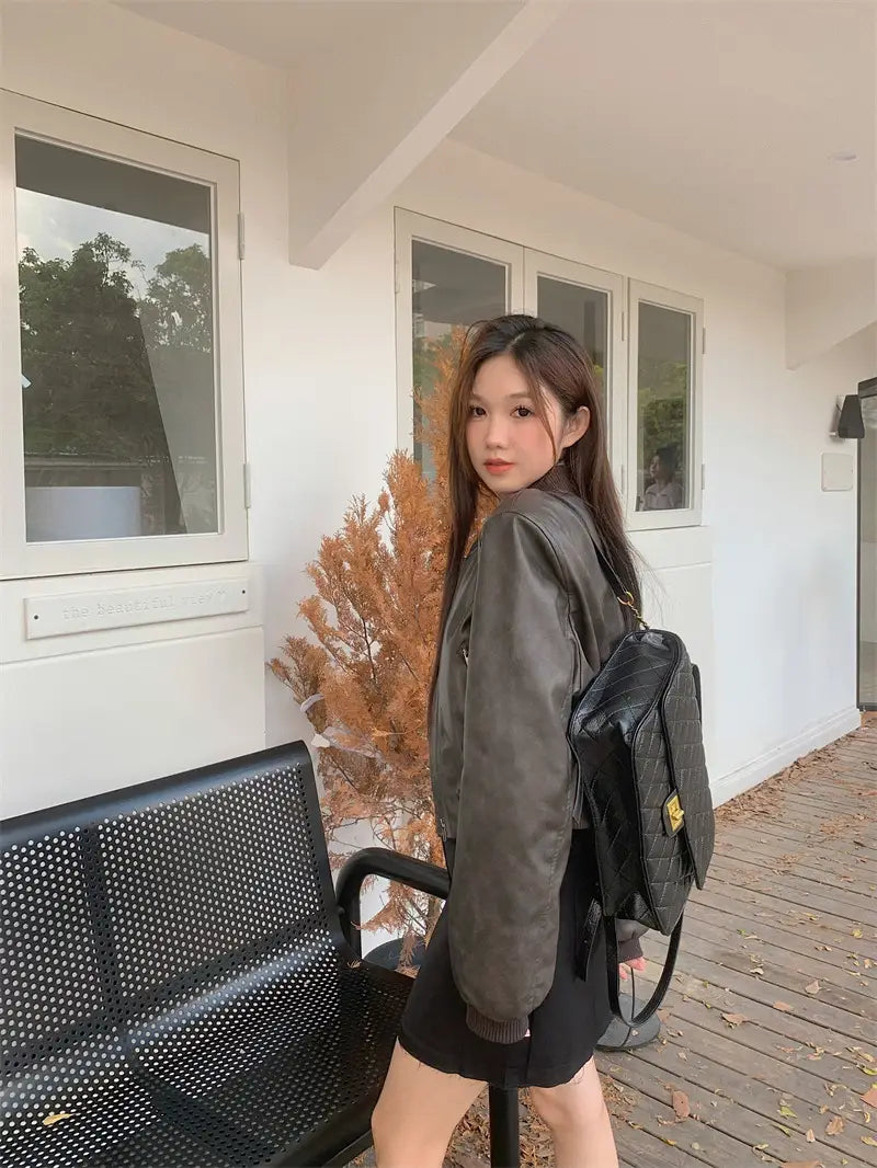 black quilted leather backpack with gold-tone hardware shown from the back complementing a faux leather bomber jacket retro biker style.