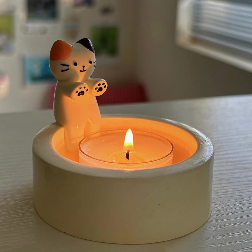 Cute calico cat candlestick holder ceramic kitten tea light stand with a glossy ceramic finish and lit tea light inside featuring a playful paw print design.