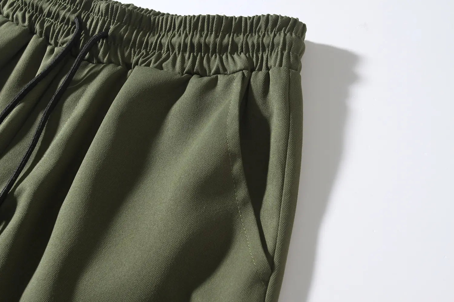 Mens multi pocket cargo work pants in olive green with a relaxed textured fabric, elastic waistband, and drawstring for adjustable fit.