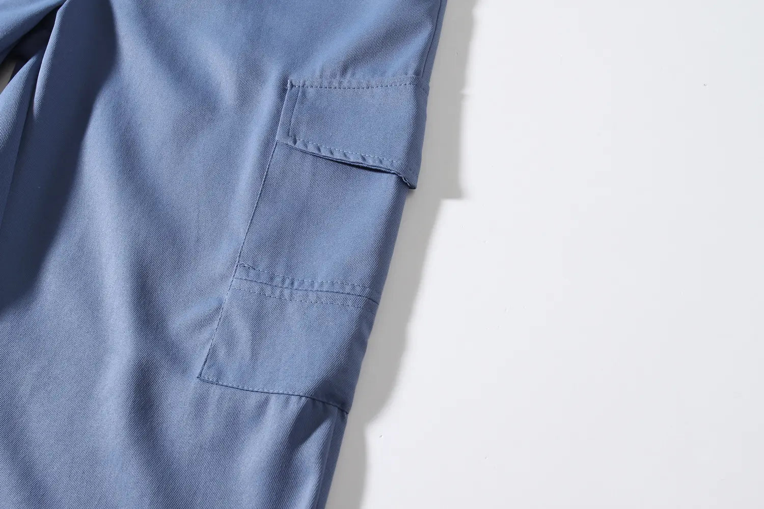 Mens multi pocket cargo work pants in blue denim featuring two flap pockets on the back side.