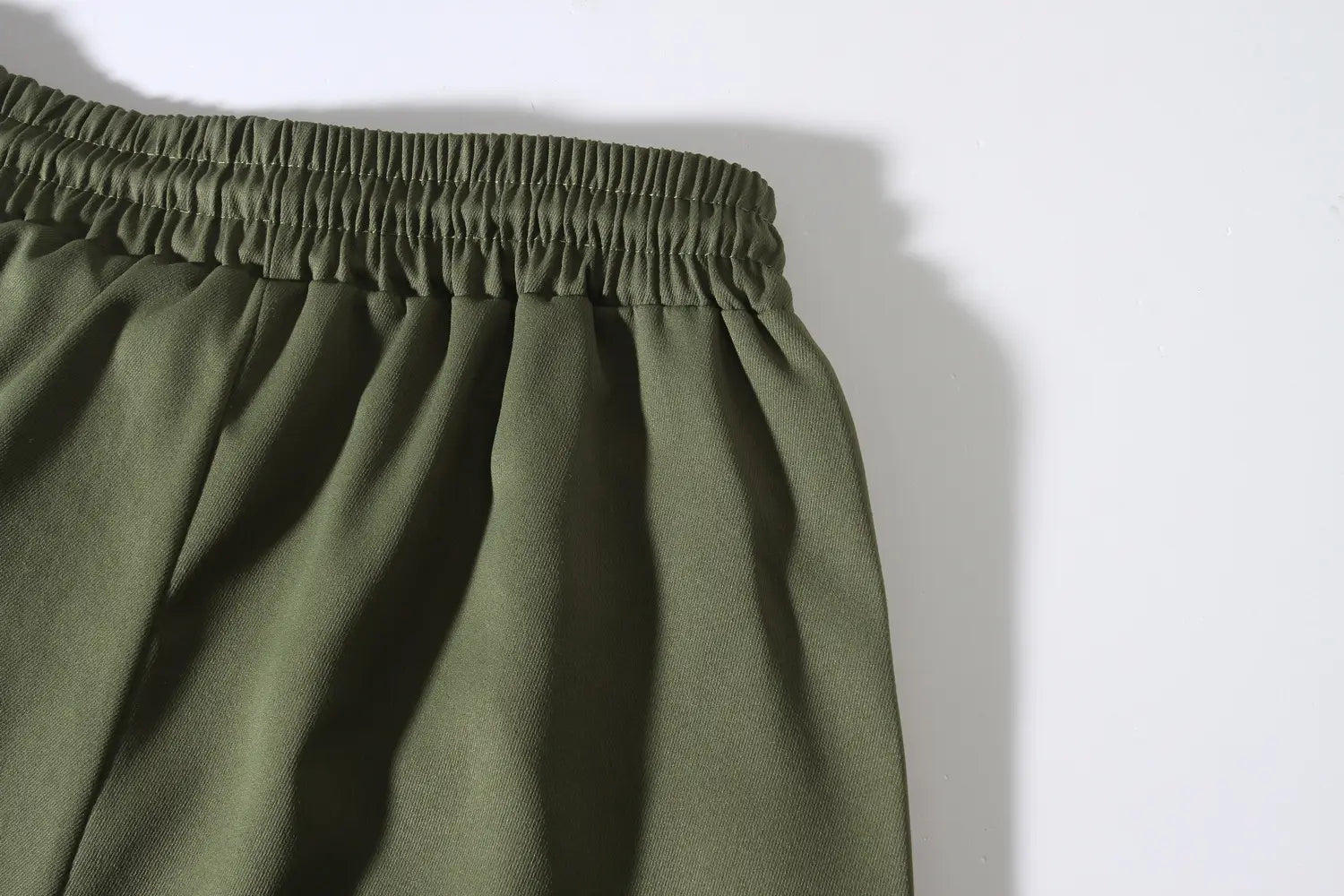 Mens multi pocket cargo work pants in olive green with elastic waist and soft flowing fabric texture.