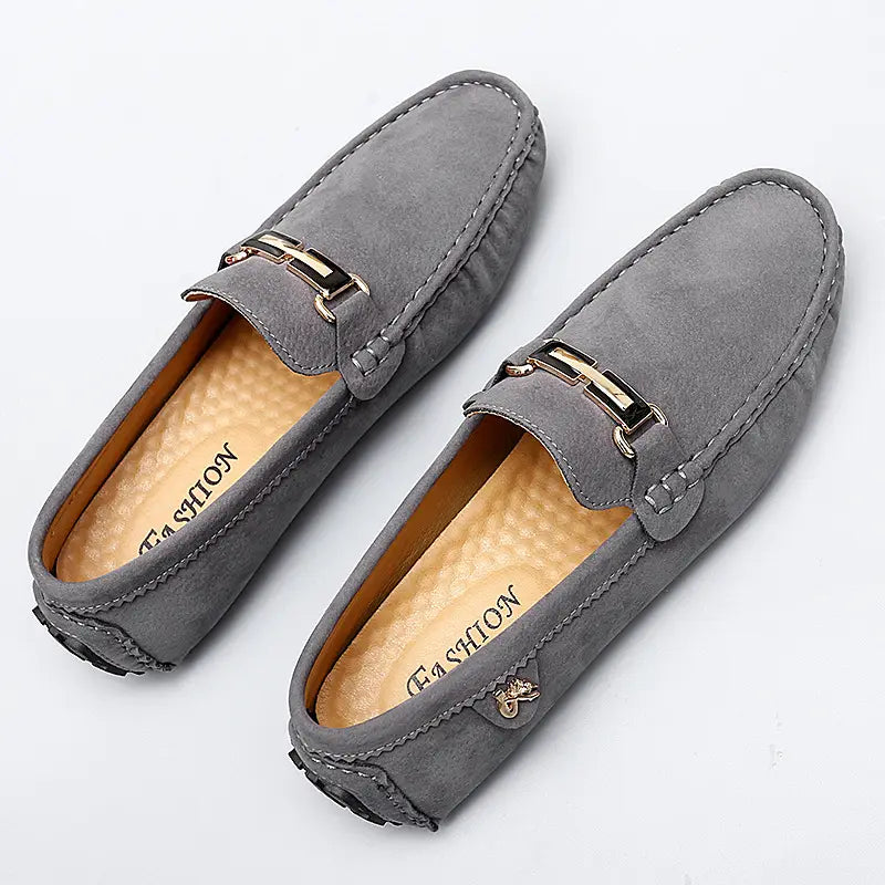 Herren-Slipper aus Samtleder mit Horsebit-Design mit grauem Samtmaterial, goldfarbenem Metall-Schnallen und detaillierter Naht für ein handgefertigtes Gommino-Schuhdesign.