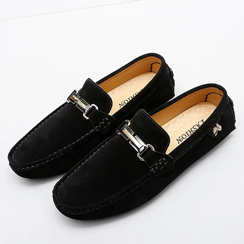 Herren-Slipper aus Samtleder mit Horsebit-Design in Schwarz, mit einer silberfarbenen Metallschnalle und abgesetzter weißer Ziernähung.